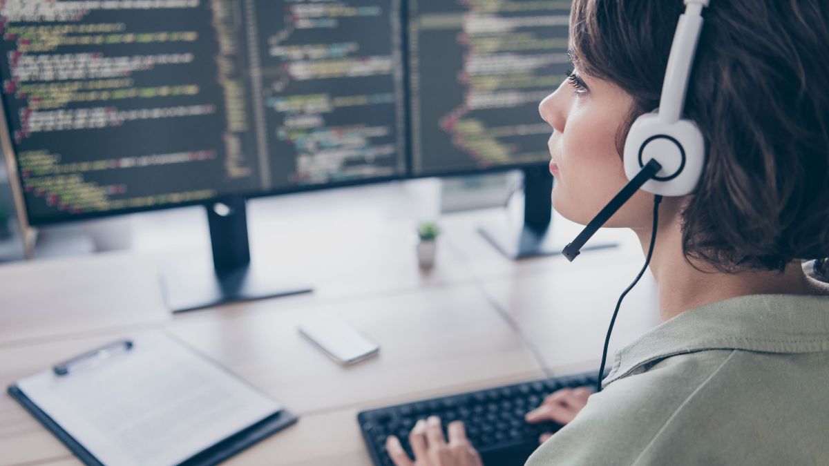 Frau mit Headset vor zwei Bildschirmen